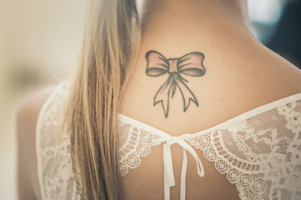 A picture of a woman with a ribbon tattoo on the back of her neck.